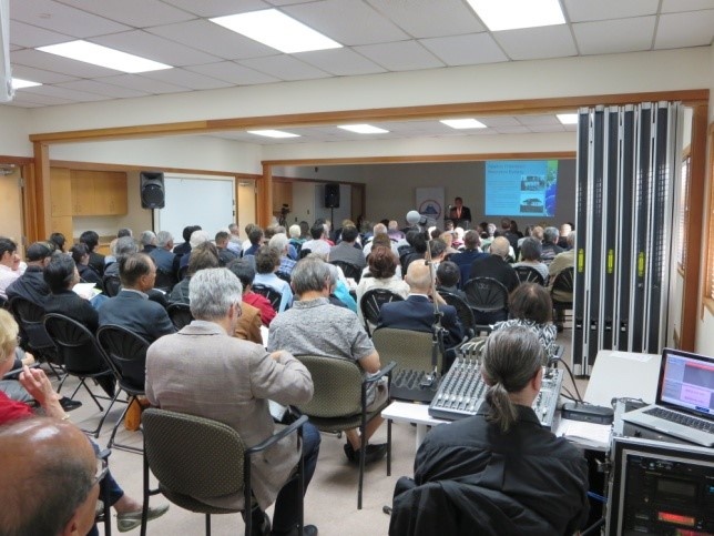 Full house audience listening and taking notes on the presentation